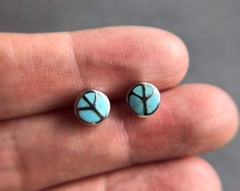 May include: A pair of silver peace sign earrings with turquoise inlay.