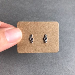 May include: A pair of silver stud earrings with a delicate, intricate design. The earrings are small and dainty, perfect for everyday wear.