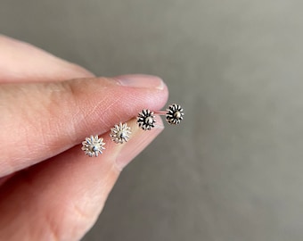 Peut inclure: Trois anneaux de nez en argent avec un petit motif de fleur. Les fleurs ont un centre surélevé et sont de tailles légèrement différentes.
