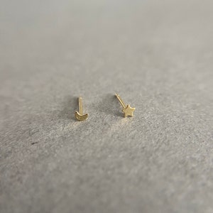 May include: A pair of gold earrings, one shaped like a crescent moon and the other shaped like a star.