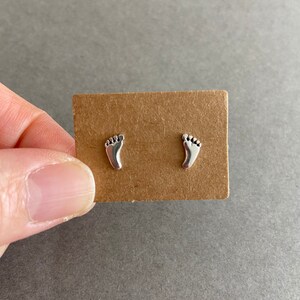 May include: A pair of silver stud earrings shaped like footprints.