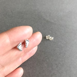 May include: A pair of silver stud earrings featuring a small footprint design.