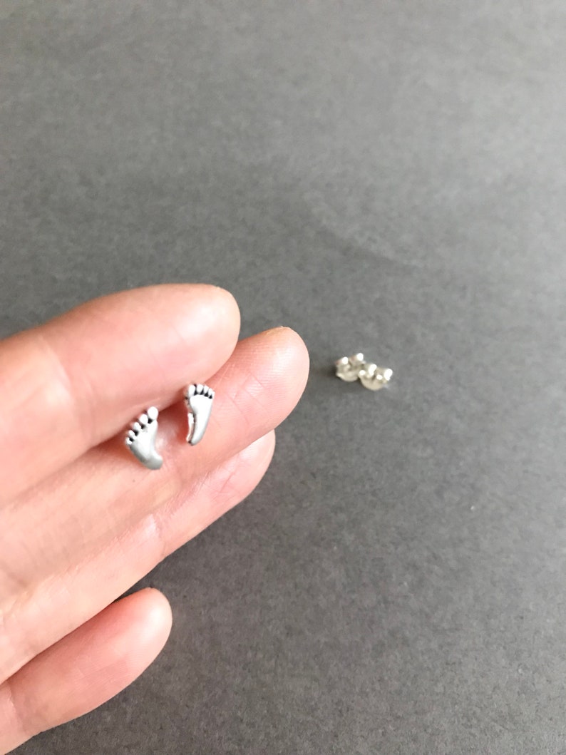 May include: A pair of silver stud earrings featuring a small footprint design.