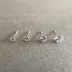 May include: Four silver nose studs with clear round rhinestones of varying sizes.