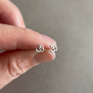 May include: A pair of silver earrings with a stylized Om symbol design.