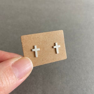 May include: A pair of silver cross stud earrings on a brown card.