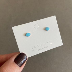 May include: A pair of light blue cloud-shaped earrings on a white card with the text "JEWELRY" and "Made in Korea".