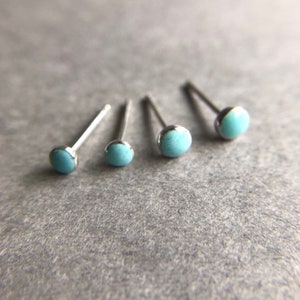 May include: Four pairs of silver stud earrings with light blue round stones.