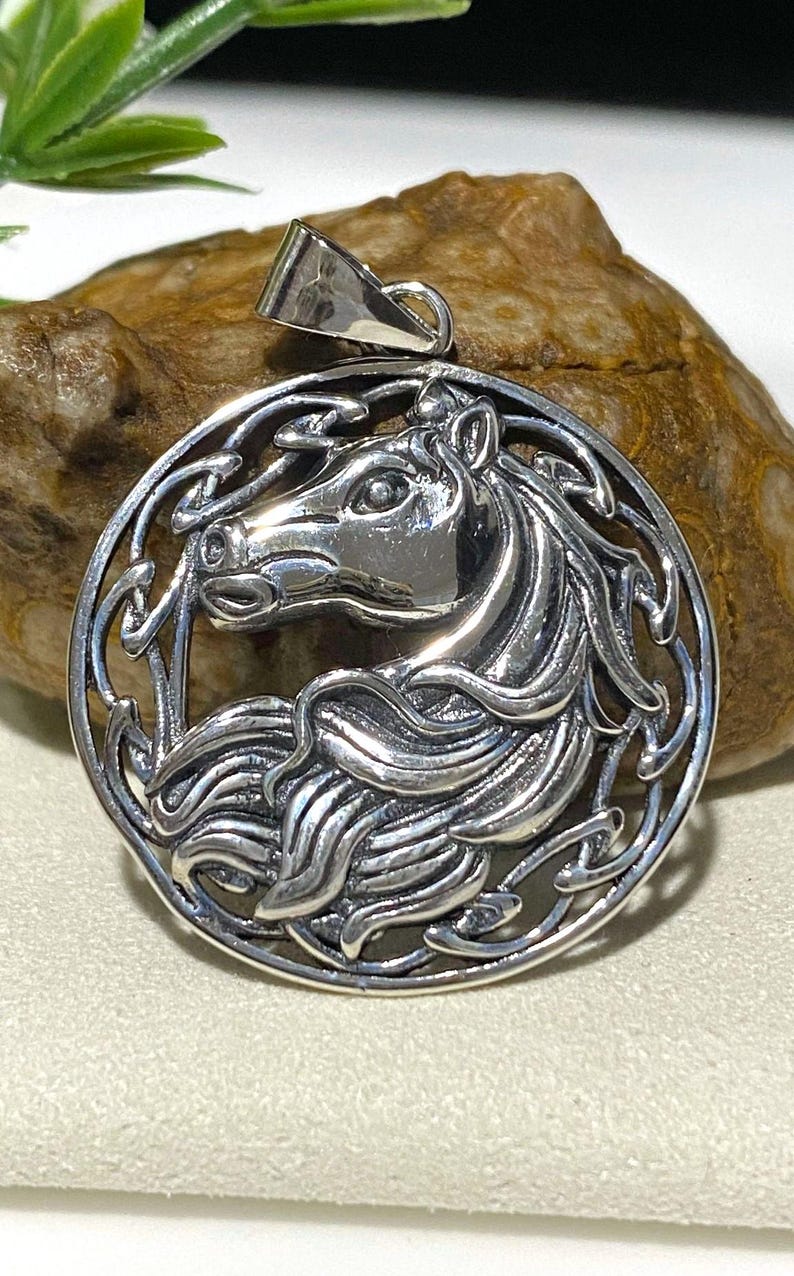 May include: Silver pendant featuring a detailed Celtic knot design with a horse's head in the center.