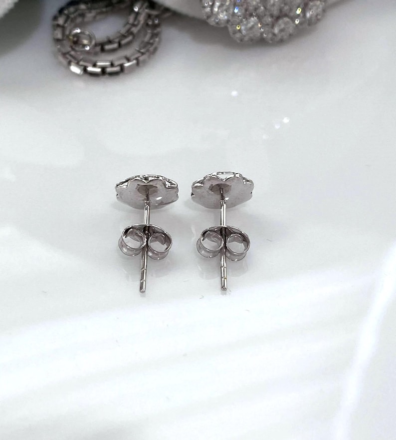 Puede incluir: Un par de pendientes de plata con un dise&ntilde;o floral. Los pendientes tienen un cierre de poste y mariposa. Los pendientes est&aacute;n sobre una superficie blanca.