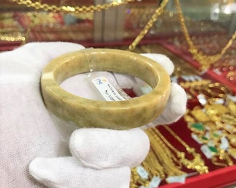 Puede incluir: Un brazalete de jade verde claro con una etiqueta blanca que dice "NATURAL JADE No. 11251".