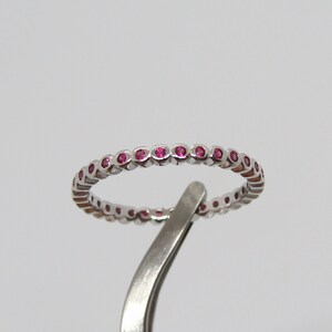 May include: A silver band ring with a row of small pink gemstones.