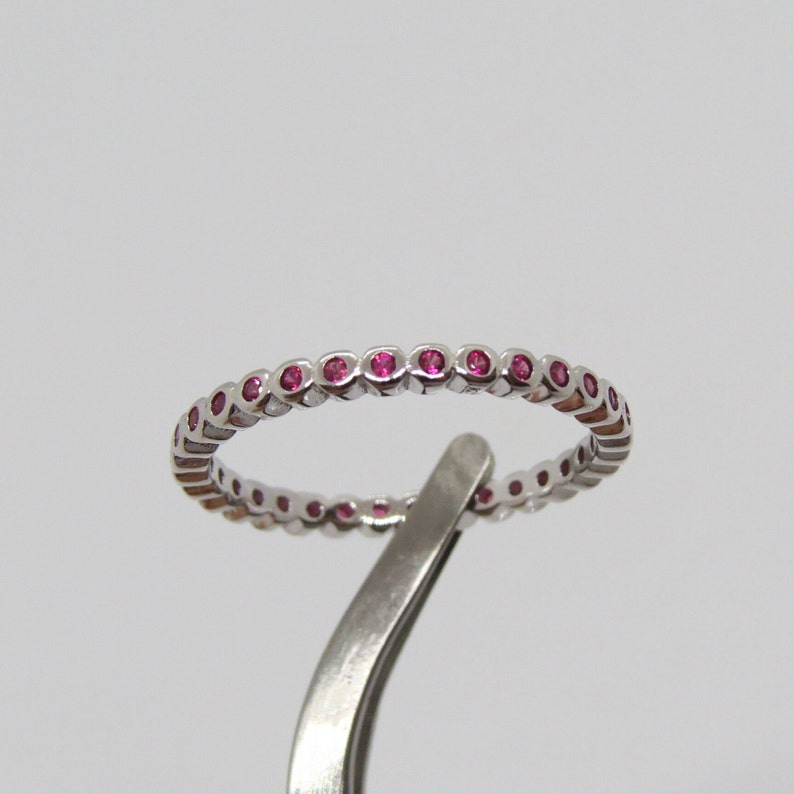 May include: A silver band ring with a row of small pink gemstones.