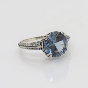 May include: A silver ring with a blue gemstone set in a filigree design.