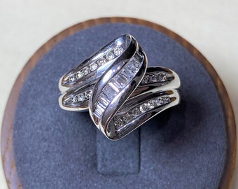 Könnte beinhalten: Ein silberner Ring mit einem Doppelband-Design, besetzt mit Baguette- und Runddiamanten.