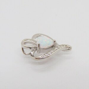 May include: A silver heart-shaped pendant with a white opal gemstone and clear cubic zirconia accents.