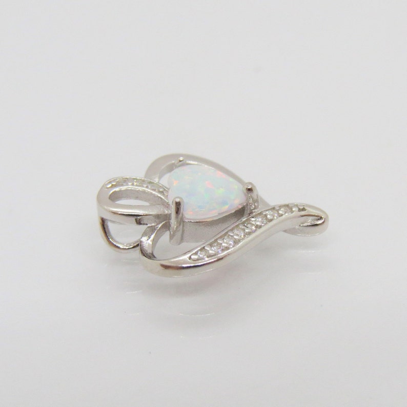 May include: A silver heart-shaped pendant with a white opal gemstone and clear cubic zirconia accents.