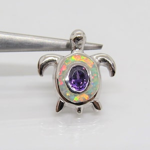 May include: A silver turtle pendant with a white opal shell and a purple amethyst gemstone in the center.
