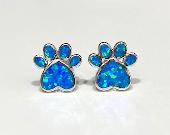 May include: A pair of silver stud earrings with blue opal paw print designs.