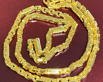May include: A gold chain necklace with a box chain design. The chain is made of interlocking square links with a decorative pattern.