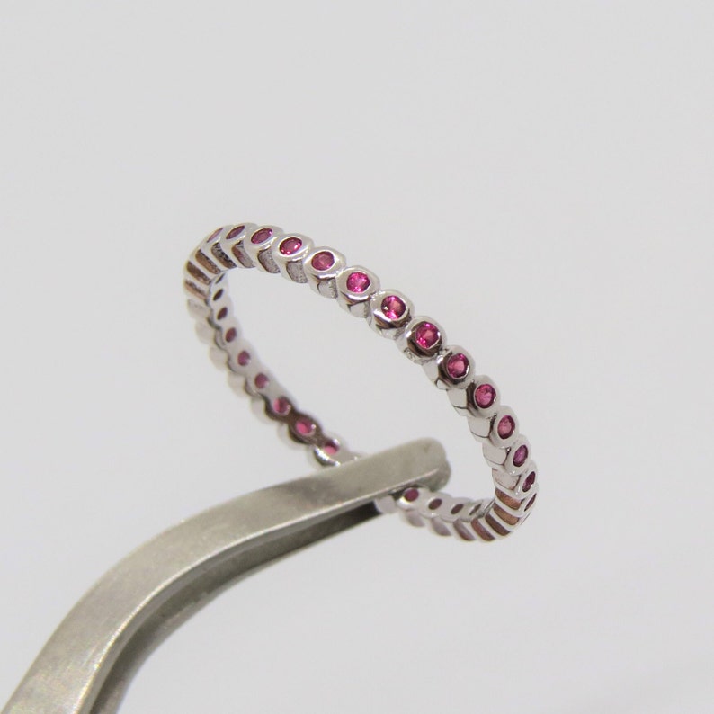 May include: A silver band ring with a row of small pink gemstones.