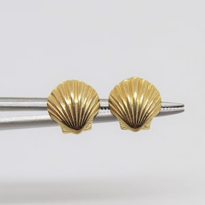 May include: A pair of gold-tone seashell stud earrings. The earrings are small and delicate, and they are perfect for adding a touch of elegance to any outfit.