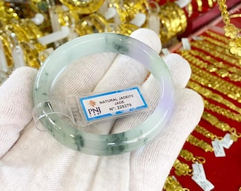 May include: A green jadeite jade bangle with white and green swirls. The bangle is labeled "NATURAL JADEITE JADE N°: 226279"