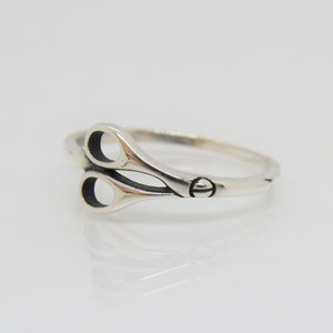 May include: A silver ring with a pair of scissors design.