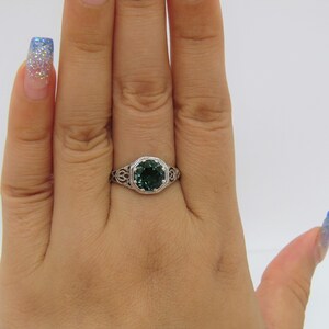 May include: A silver ring with a green gemstone set in a filigree design.