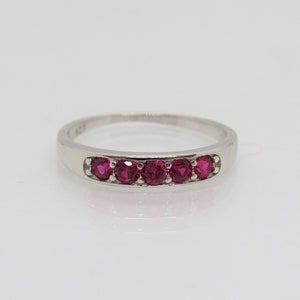 以下が含まれることがあります： 5つの赤い宝石が並んだシルバーのバンドリングです。