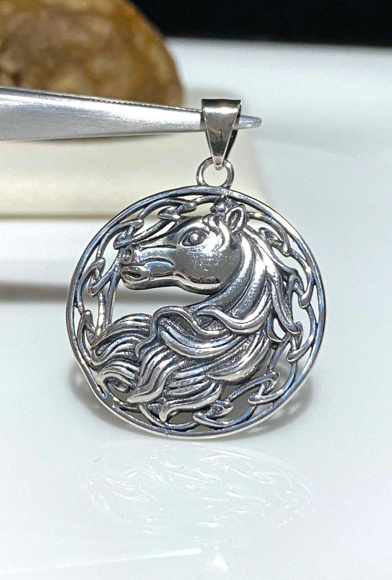 May include: Silver pendant featuring a detailed Celtic knot design with a horse's head in the center.