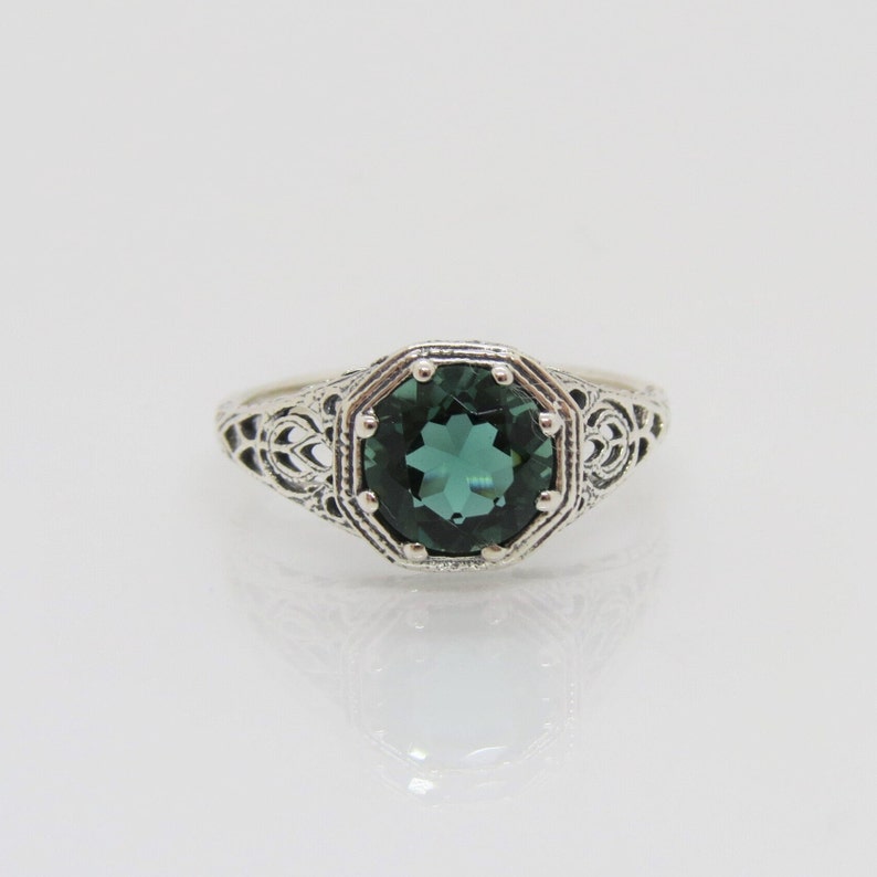 May include: A silver ring with an octagonal green gemstone set in a filigree design.