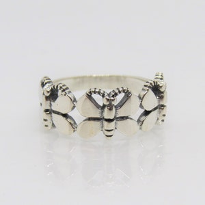 May include: A silver ring with three butterfly designs. The butterflies are detailed and have a textured finish.