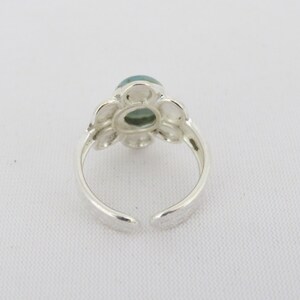 May include: Silver ring with a green gemstone set in a flower design.