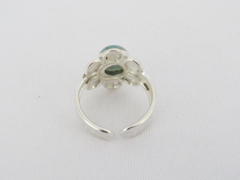 May include: Silver ring with a green gemstone set in a flower design.
