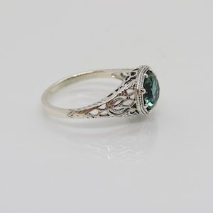 May include: A silver ring with a filigree design and a green gemstone.