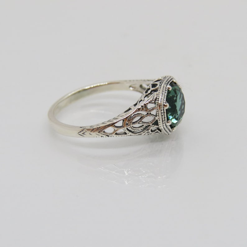 May include: A silver ring with a filigree design and a green gemstone.