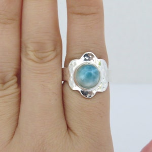 May include: A silver ring with a blue and white gemstone set in a textured flower-shaped setting.