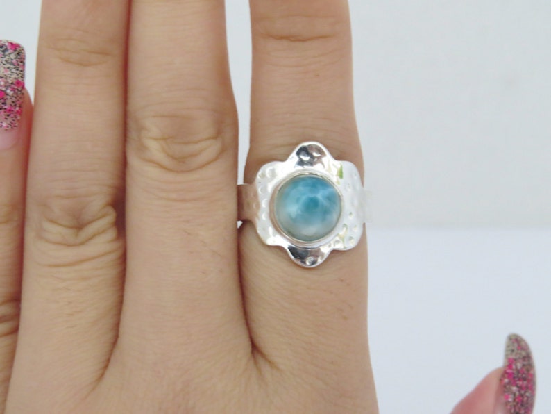 May include: A silver ring with a blue and white gemstone set in a textured flower-shaped setting.