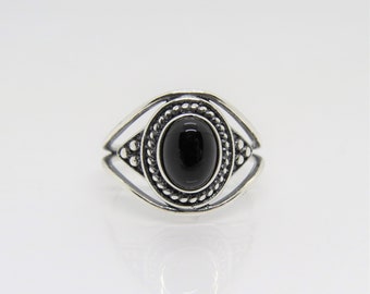 May include: A silver ring featuring a black oval gemstone set in a beaded bezel. The ring has a delicate, openwork design.
