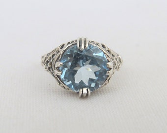 May include: A silver ring with a light blue gemstone set in a filigree design.