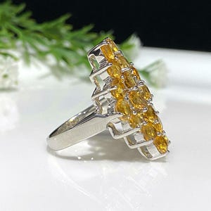 May include: A silver ring with a cluster of orange gemstones set in a geometric design.