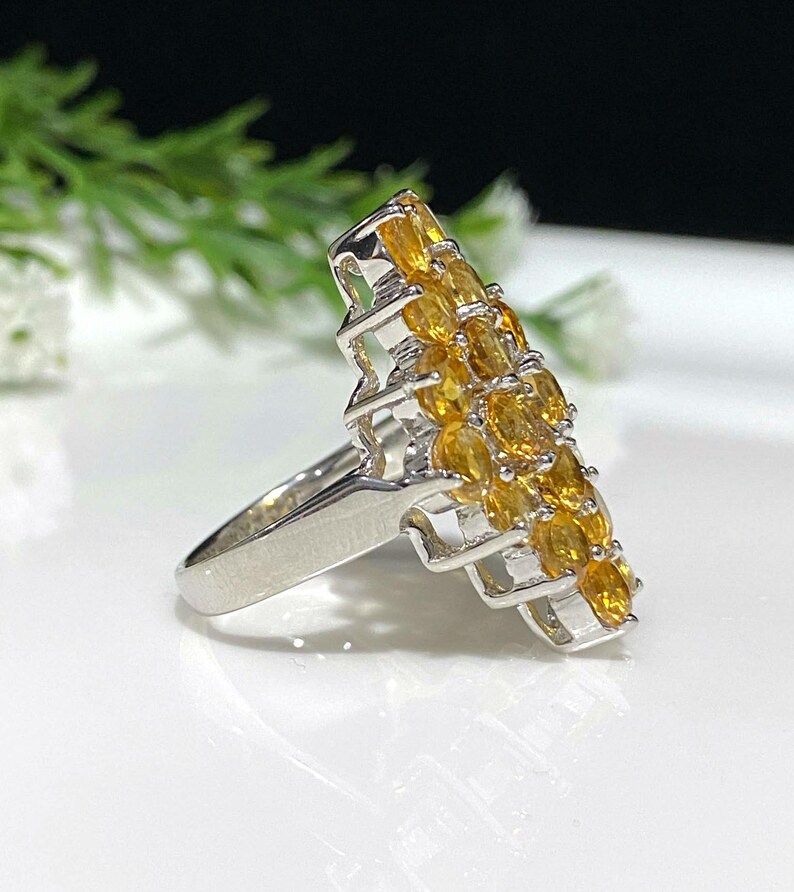 May include: A silver ring with a cluster of orange gemstones set in a geometric design.