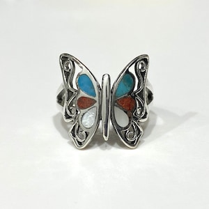 May include: A silver butterfly ring with turquoise, red, and white inlay. The butterfly wings are detailed with intricate designs.