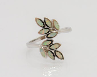Puede incluir: Un anillo de plata con un diseño de dos ramas de hojas hechas de piedras de ópalo blanco.