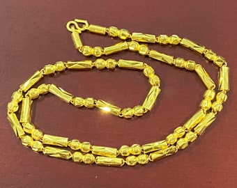 May include: A gold chain necklace with alternating round and rectangular links. The chain is made of a shiny, polished metal.