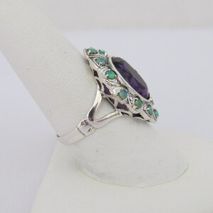 May include: A silver ring with a large purple amethyst gemstone surrounded by smaller green opals.