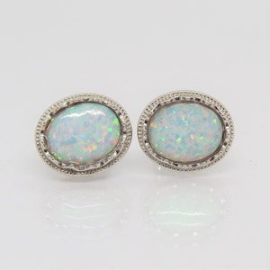 May include: A pair of silver earrings with white opal stones set in a round bezel setting.
