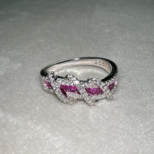 May include: A silver ring with a twisted band set with small clear stones and five pink baguette-shaped stones.