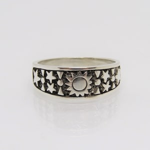 May include: A silver ring with a sun and star design. The ring is made of sterling silver and has a polished finish.